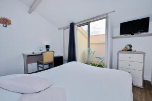 巴拉吕克莱班Azur Hotel的卧室配有白色的床、书桌和窗户。