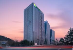 青岛青岛国际创新园智选假日酒店的上面有绿色标志的高楼