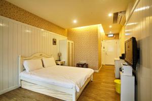 Ruifang永远是晴天民宿的卧室配有白色的床和电视。
