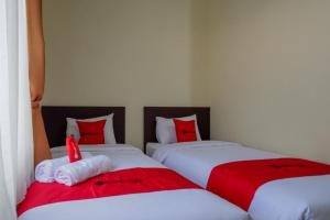 KebumenRedDoorz Syariah near Alun Alun Kebumen的配有红色和白色枕头的客房内的两张床