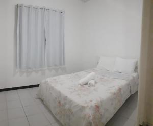 巴拉杜斯科凯鲁斯CHALÉS ENCANTOS DA ILHA的一间卧室配有一张带白色毯子的床和窗户。
