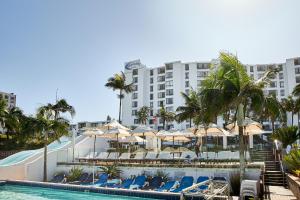 德班Breakers Resort的酒店前方的游泳池配有椅子和遮阳伞