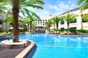 艾恩艾因罗塔纳酒店的一座大型游泳池,在一座建筑前种有棕榈树