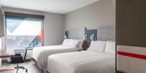 纳什维尔avid hotels - Nashville Airport, an IHG Hotel的酒店客房设有两张床、一张书桌和一个窗户。