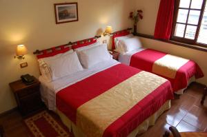 马德普拉塔西雷纳斯酒店的一间卧室配有两张红色和白色床单