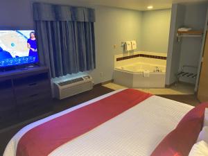 GarnettGarnett Hotel & RV Park的一间酒店客房,配有一张床、一台电视和一个浴缸
