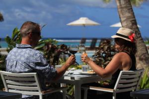 拉罗汤加Moana Sands Lagoon Resort - Adults Only的坐在桌子上戴酒杯的男人和女人