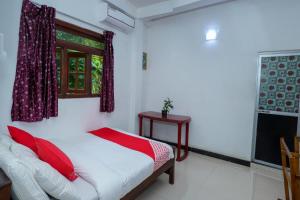 康提Kandyan Nethu Stay的一间卧室配有一张带红色枕头的床和一扇窗户