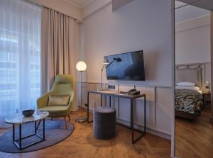 柏林Classik Hotel Alexander Plaza的酒店客房配有书桌、椅子和电视。