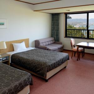 宫岛宫岛森林酒店的酒店客房设有两张床、一张沙发和一张桌子。