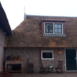 OpeindeB&B De Herenboer的一座带窗户和椅子的屋顶建筑