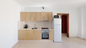 普拉亚布兰卡Blancazul La Rociega的厨房配有木制橱柜和白色冰箱。