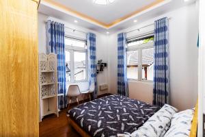 大叻Karry's House的一间卧室配有床和2个带蓝色窗帘的窗户。