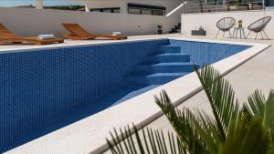 特罗吉尔Villa Helena的一座位于房子一侧的蓝色瓷砖游泳池