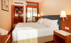 巴塞罗那巴塞罗那昂特扎NH酒店的卧室配有一张白色大床和镜子