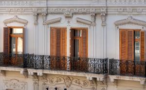 瓦伦西亚NH Collection Colón Valencia的白色的建筑,设有棕色百叶窗和阳台