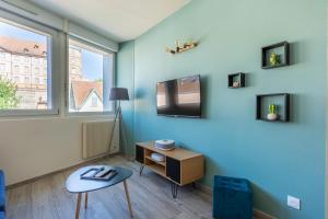 蒙贝利亚尔Le 15-GregIMMO-Appart'Hôtel的一间设有蓝色墙壁、电视和桌子的客房