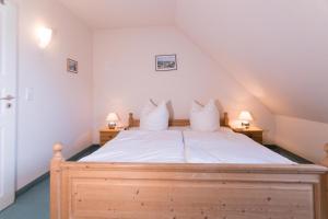 欧巴德伍斯图Ferienhaussiedlung Strandperlen Küstenhof 2b (Typ V)的一间卧室配有一张带白色床单和两盏灯的床。