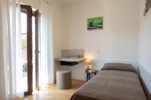西斯蒂亚纳Residence Mare Azzurro Sistiana的一间卧室配有一张床、一张桌子和一个窗户。