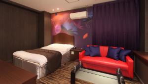 宇都宫雷斯特太阳城酒店（仅限成人）的酒店客房,配有一张床和一张红色椅子