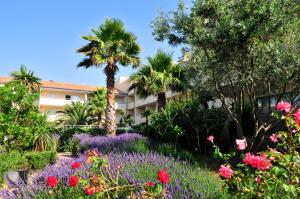 勒格罗-迪鲁瓦五月花公寓式酒店的一座花园,在一座建筑前种有鲜花和棕榈树