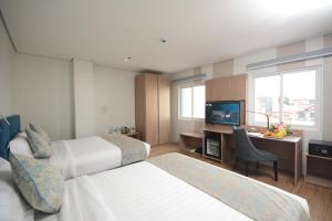达沃市Blue Lotus Hotel的酒店客房设有两张床和一张书桌及电视