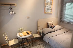 台南纳春公寓民宿的小房间设有一张床、一张桌子和椅子
