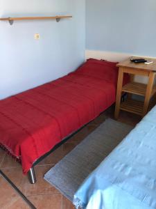 乌马格Apartman Ana的一张红色的床,坐在一张桌子上