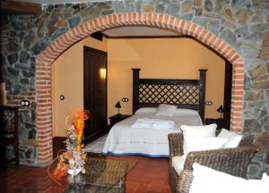 莱德斯马Hotel Rural El Rocal的一间卧室设有一张床和石墙