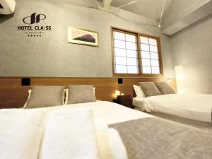 广岛HOTEL CLA-SS HIROSHIMA-OZU的酒店客房设有两张床和窗户。