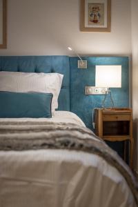 斯特拉斯堡Gite **** des Bains的一张带蓝色床头板的床和一张带台灯的桌子