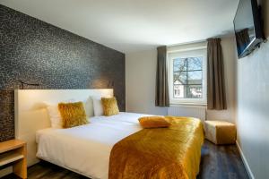 埃彭Aparthotel Ons Epen的卧室配有一张带黄色枕头的大型白色床。