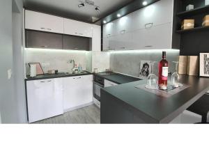 布尔加斯K&K Stylish Elegance的厨房配有白色橱柜和1瓶位于柜台上的葡萄酒