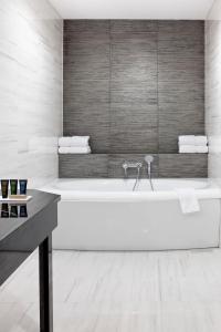 克拉科夫大都会精品酒店的白色的浴室设有浴缸和水槽。