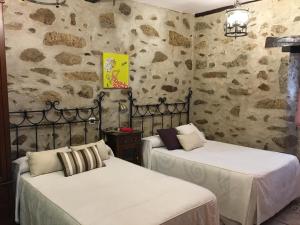 坎德拉里奥Casa Rural La Antigua Tahona的石墙客房的两张床