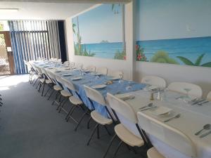 梅林布拉南海汽车旅馆的客房设有一张长桌子、白色的椅子和蓝色的桌子。