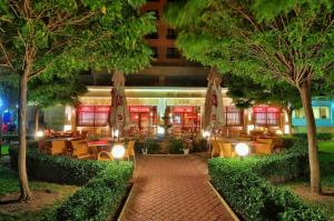 金沙Hotel Paradise Green Park Allinclusive Light的一间晚上带桌椅和树木的餐厅