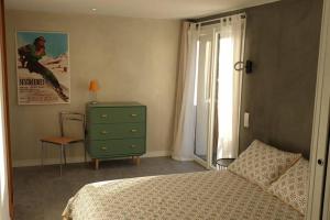 埃姆布能Le petit appart de Pomme的一间卧室配有一张床、一个梳妆台和一扇窗户。