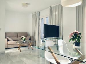 格拉纳达Domus Apartamentos Granada con parking gratuito en pleno centro的客厅配有玻璃桌和电视