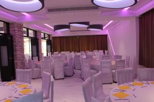 珊瑚湾佩特撒公寓式酒店的宴会厅配有白色桌椅和紫色照明