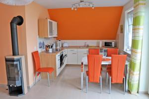 马林费尔德Ferienhaus Müritzbrise / OG-Appartement的厨房配有橙色椅子、桌子和炉灶