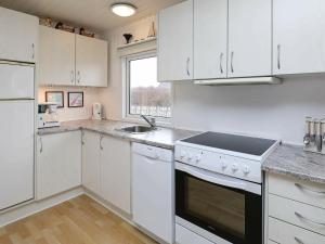 森讷维4 person holiday home in Ringk bing的厨房配有白色橱柜、水槽和炉灶。