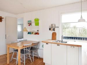 瓦伊厄斯斯特兰德4 person holiday home in Vejers Strand的厨房配有白色橱柜和木桌
