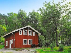 卢恩斯基尔Four-Bedroom Holiday home in S-Uddvalla的红色的房子,设有白色的窗户和桌子