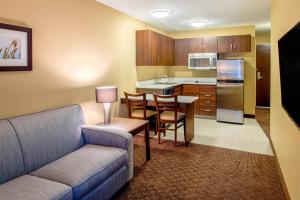 雷德迪尔红鹿市温德姆麦克罗特套房酒店的带沙发和桌子的客厅以及厨房。
