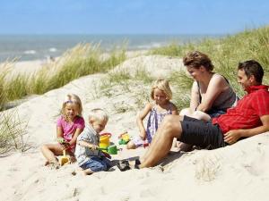 灵克宾8 person holiday home in Ringk bing的坐在沙滩上的一家人