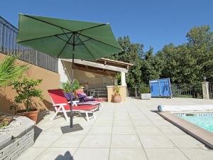 莱德农Modern Villa with Private Swimming Pool in L denon的一个带绿色遮阳伞和椅子的庭院,毗邻一个游泳池