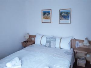 上特劳恩荷花公寓式酒店的卧室配有一张白色床,墙上挂有两张照片