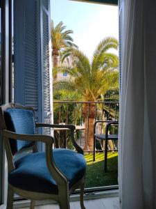 戛纳普罗旺斯酒店的客房设有带椅子和棕榈树的窗户。