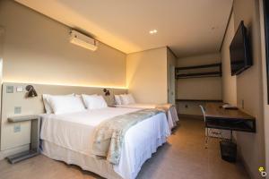 卡皮托利乌NAIM Hotel的一间酒店客房,配有一张大床和一台平面电视